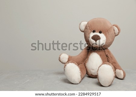 Cute teddy bear on light grey marble table, space for text
