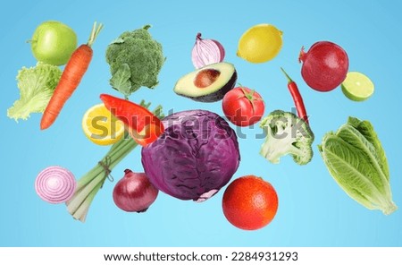 Many fresh vegetables and fruits falling on light blue background
