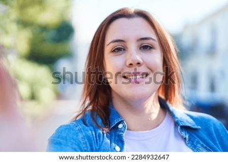 Young beautiful plus size woman smiling confident making selfie by camera at street