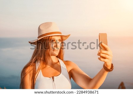 Woman travel sea. Happy tourist in hat enjoy taking picture outdoors for memories. Woman traveler posing on the beach at sea surrounded by volcanic mountains, sharing travel adventure journey.