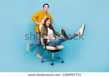 Full body length photo cadre of funny overjoyed playing couple push boss chair comfort activity fast speed moving isolated on blue color background Royalty-Free Stock Photo #2284941723