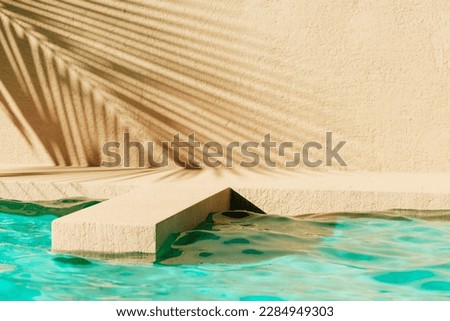 Tropical summer background with concrete wall, pool water and palm leaf shadow. Luxury hotel resort exterior for product placement. Outdoor vacation holiday house scene, neutral architecture aesthetic