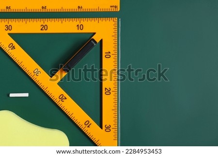 Protractor, sponge, chalk and ruler on green chalkboard, flat lay. Space for text