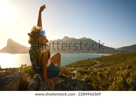 Portrait Of Woman With Backpack On Vacation Taking A Break On Hike By Sea Stretching Arms In The Air
