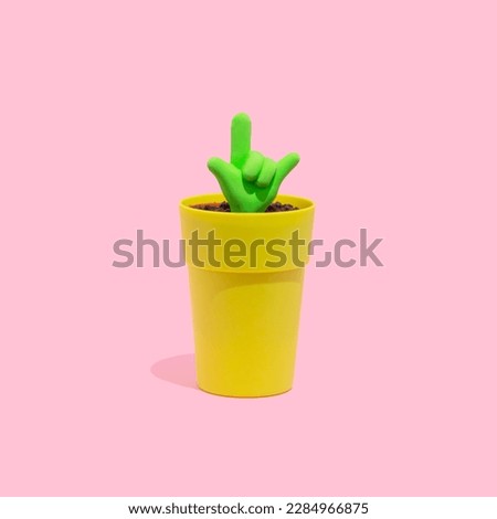 Fluorescent green ILY, I love you symbol icon growing from a small pot on a pastel  pink background. Hand gestures, love concept.