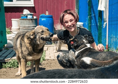 Dog at the shelter. Animal shelter volunteer takes care of dogs. Lonely dogs in cage with cheerful woman volunteer.  Royalty-Free Stock Photo #2284972633