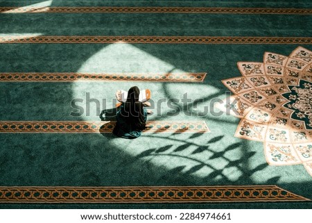 A Muslim woman praying inside the mosque. Royalty-Free Stock Photo #2284974661