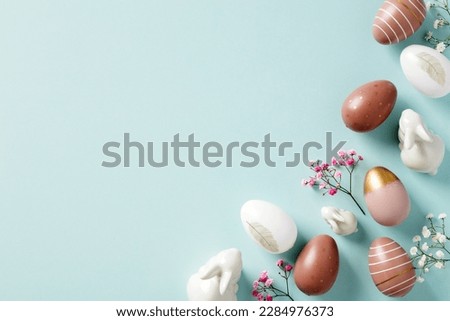 Happy Easter frame made of Easter eggs, bunnies, flowers on light blue background. Easter flat lay composition, top view.