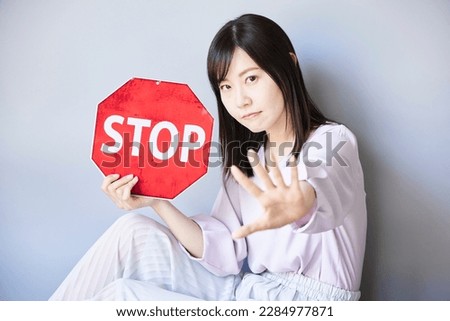 Asian woman holding STOP traffic sign