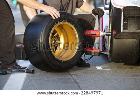 Mechanics of a pit crew changing the slicks of a race car during a pitstop Royalty-Free Stock Photo #228497971