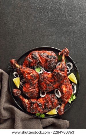 Indian style tandoori chicken on plate over dark stone background with copy space. Chicken legs marinated in yogurt and spices. Top view, flat lay Royalty-Free Stock Photo #2284980963