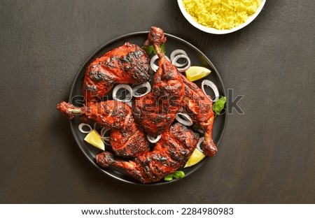 Indian style tandoori chicken on plate over dark stone background. Chicken legs marinated in yogurt and spices. Top view, flat lay Royalty-Free Stock Photo #2284980983