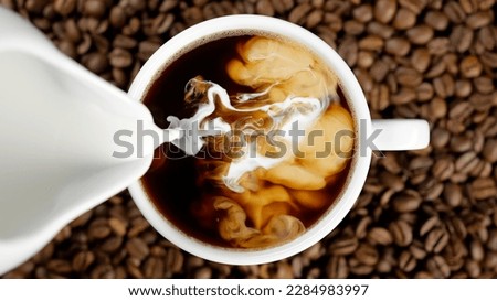 Pouring milk in coffee cup, top view Royalty-Free Stock Photo #2284983997
