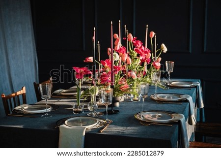 Festive dinner table is served dishes and cutlery and decorated with flowers tulips and greenery, candles. Birthday celebration. Family holidays in modern dining room. Stylish spring party. Wedding. Royalty-Free Stock Photo #2285012879