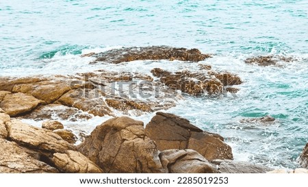 Panoramic nature banner. Waves on coastal rocks close-up. Turquoise rolling wave slamming on the rocks of the coastline. Rocky coast of the island