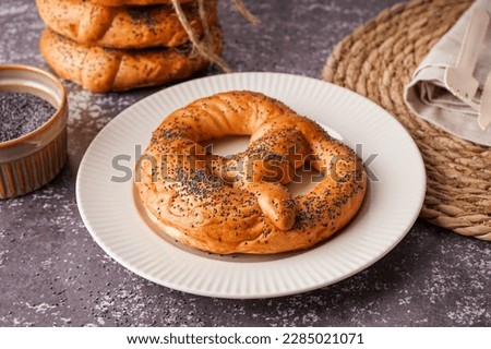 Plate with tasty pretzel and poppy seeds on grunge background