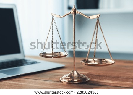 Symbolizing justice and legal authority, golden balanced scale on desk with laptop in law office background, reflecting concept of equality and fair judgment by lawyer and judge. equility