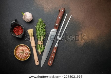 vintage kitchenware kitchen utensils: Meat Fork and Butcher Cleaver and herbs knife, ingredients for grilling meat steak on a dark background. place for text, top view, Royalty-Free Stock Photo #2285031993
