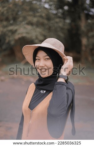 portrait of young asian muslim woman enjoying holiday and smiling in village park