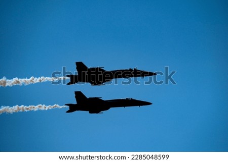 FA-18 Superhornet Jet silhouettes with white smoke with a blue sky at Sun’N Fun 2023. Royalty-Free Stock Photo #2285048599