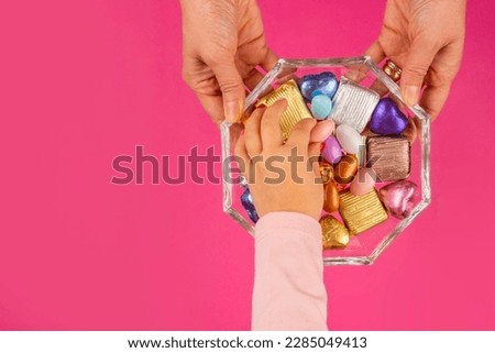 Sugar feast concept, top view image of sugar feast concept. Woman hands holding glass sweet bowl, kid hand taking one of the almond dragee. Traditional Turkish Ramazan or ramadan festive holiday. Royalty-Free Stock Photo #2285049413