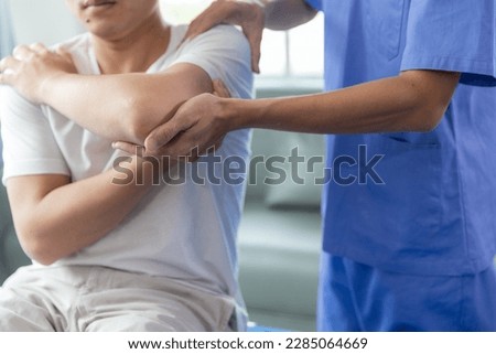 Doctor or Physiotherapist working examining treating injured arm of athlete male patient, stretching and exercise, Doing the Rehabilitation therapy pain in clinic. Royalty-Free Stock Photo #2285064669