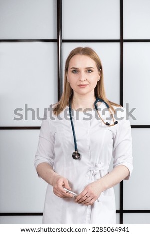 Portrait of a young woman doctor in a white uniform with a stethoscope around her neck. Family doctor, cardiologist or nurse