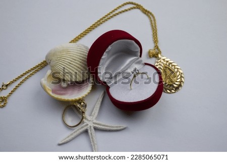 Ring in box, ring in red box, placed on white background.  pearl, mussel, star, gold necklace