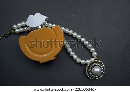 Perfume and pearl necklace.  Perfume and pearl necklace placed on a black background.  surface