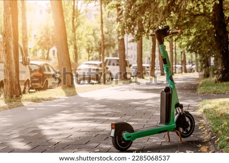 Electric Scooter for Rental on Sidewalk by Road with Many Cars in Green City. Electric Ride Sharing E Scooter.  Royalty-Free Stock Photo #2285068537