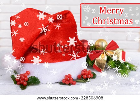 Leaves of mistletoe with Christmas hat on table on brick wall background