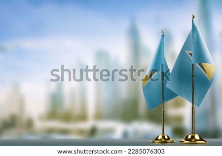 Small flags of the Saint Lucia on an abstract blurry background.