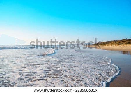 Beautiful panorama of the Peregian Beach nestled against the dunes of a pristine white sand beach with surfing breaking waves on the Sunshine Coast, Queensland, Australia.