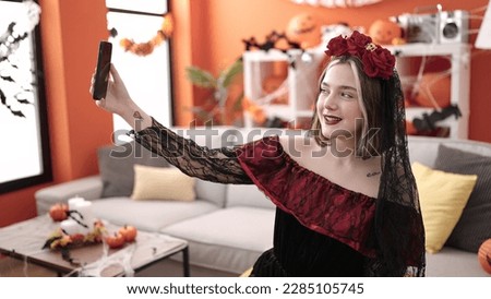 Young blonde woman wearing katrina costume making selfie by smartphone at home
