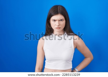 Young caucasian woman standing over blue background skeptic and nervous, frowning upset because of problem. negative person.  Royalty-Free Stock Photo #2285113239