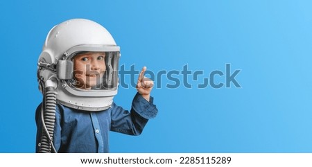 A small child imagines himself to be an astronaut in an astronaut's helmet.  Royalty-Free Stock Photo #2285115289