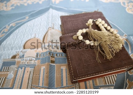 Holy Quran with prayer beads on a sajadah pad..