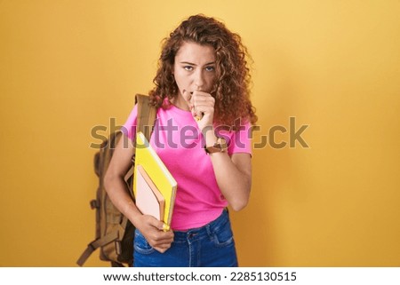 Young caucasian woman wearing student backpack and holding books feeling unwell and coughing as symptom for cold or bronchitis. health care concept. 