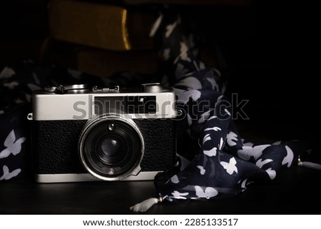 Old vintage camera  on a rustic table against a low light dark background - low light under exposed photography - selective focus
