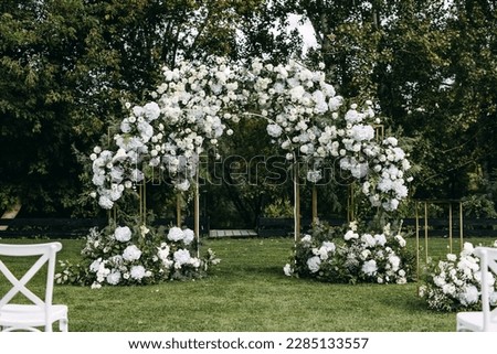 Wedding ceremony aisle with an arch decorated with flowers placed on green grass. Garden wedding venue. Royalty-Free Stock Photo #2285133557