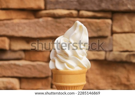 Delectable Vanilla Soft Serve Ice Cream Cone with Blurry Stone Blocked Wall in the Backdrop Royalty-Free Stock Photo #2285146869