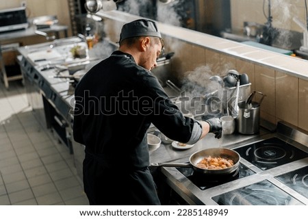 Professional kitchen in the hotel restaurant the chef is frying seafood on pan Royalty-Free Stock Photo #2285148949