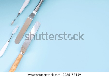 Professional set of spatulas for icing large cakes. starter kit for decorating a cake. Confectioner's tools on a blue background, pastry spatulas. Place for text Royalty-Free Stock Photo #2285153169