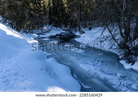 Beautiful frozen river in winter snowy forest