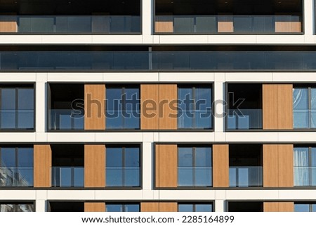 Detail for a modern multifamily building in the city center. Large number of floors. Balconies and loggias. Sunny weather