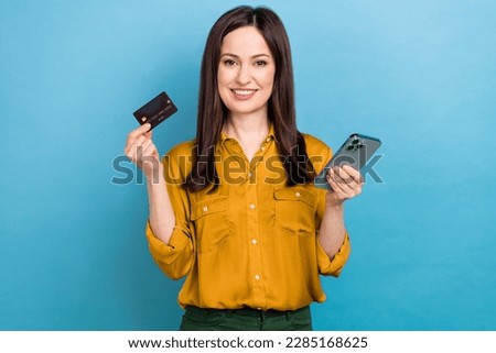 Photo of positive pretty woman wear yellow shirt online shopping apple sansung modern device isolated blue color background