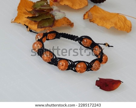 Orange bracelet on a white. Orange bracelet and leafs