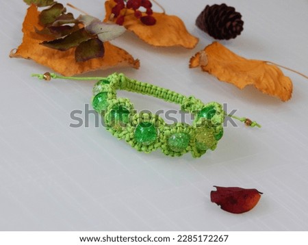 Green friendship bracelet and leafs. Green friendship bracelet on a white