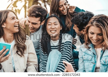 Multicultural friends having fun hanging outdoors - Happy young people talking and smiling together on summer vacation - Life style concept with guys and girls sitting in city street Royalty-Free Stock Photo #2285172343