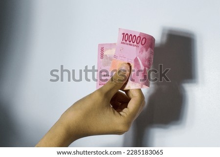hand holding indonesian money, isolated white background